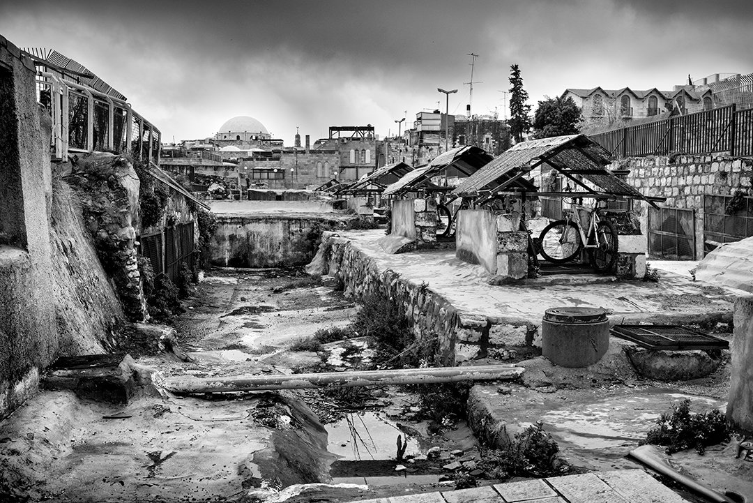 An empty space between buildings with roofs and metal structures.
